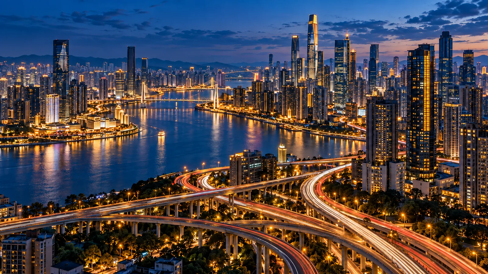 从高处俯瞰繁华都市，蓝色夜空下高楼灯火璀璨，江面倒映暖黄灯光，立交桥车流汇成长长光轨。